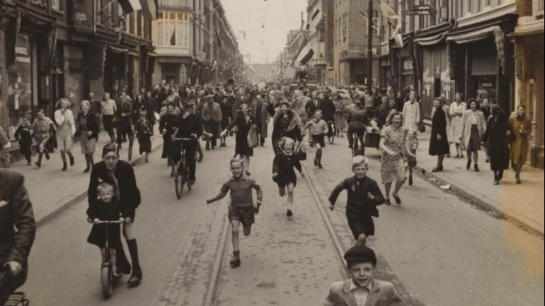 Inwoners Den Haag rennen bevrijders tegemoet. Bron: Nederlands Instituut voor Militaire Historie